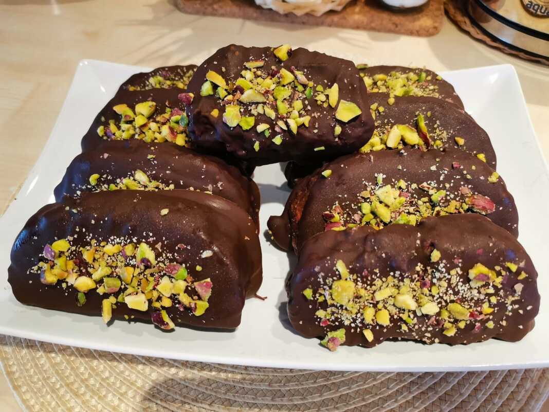 Πιάτο γεμάτο με γυαλιστερές Καριόκες με Πορτοκάλι, πασπαλισμένες με φυστίκι Αιγίνης, έτοιμες για σερβίρισμα