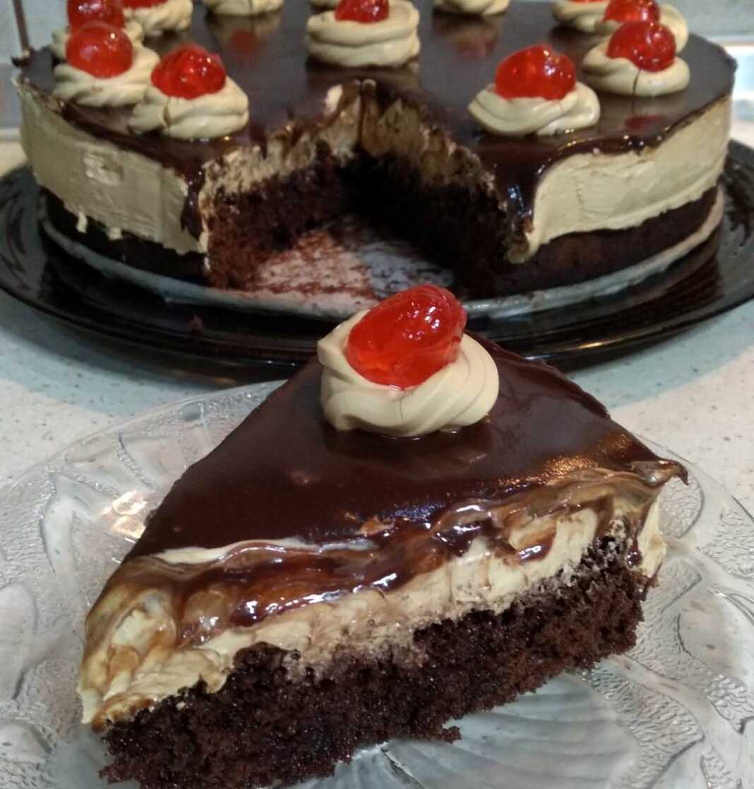 PastaTaciouKaramela Μια πλούσια πάστα ταψιού με στρώσεις σοκολατένιου παντεσπανιού, κρεμώδους καραμέλας και γυαλιστερού γλάσου σοκολάτας, έτοιμη για σερβίρισμα.