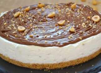 Μια τούρτα γιαουρτιού με στρώσεις κρέμας και διακόσμηση από πραλίνα φουντουκιού και ολόκληρα φουντούκια.