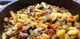 Ένα ταψί με χοιρινό κομμάτια, πατάτες και κολοκυθάκια που ψήνονται στο φούρνο.