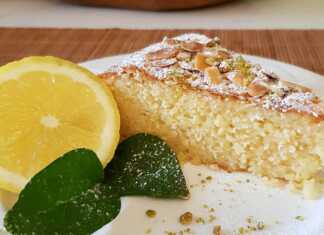 Ένα κομμάτι κέικ αμυγδάλου πασπαλισμένο με άχνη ζάχαρη και ξύσμα λεμονιού σε ένα κομψό πιάτο με λευκή σοκολάτα να διακρίνεται στην υφή του