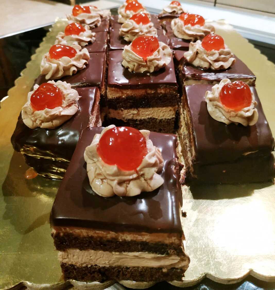 Ένα κομμάτι πλούσιας σοκολατένιας πάστας ταψιού με στρώσεις παντεσπανιού, κρέμας και γλάσου σοκολάτας.