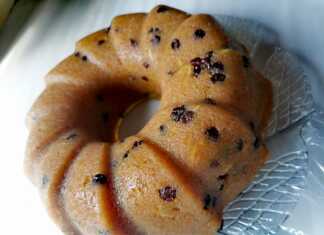 Σιμιγδαλένιος χαλβάς σε φόρμα, έτοιμος να κοπεί, με έντονο κίτρινο/πορτοκαλί χρώμα και κομματάκια σταφίδας ορατά στην επιφάνεια.