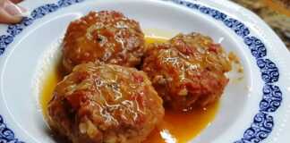 Ενα πιάτο με στρογγυλά, ροδοκοκκινισμένα κεφτεδάκια, βυθισμένα σε κόκκινη σάλτσα ντομάτας, με πράσινα μυρωδικά στο φόντο.