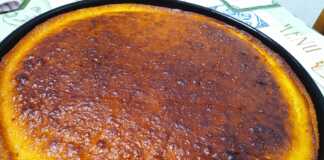 Ένα ταψί αφράτο και σιροπιαστό Ρεβανί Βέροιας, πασπαλισμένο με ινδοκάρυδο, σε ένα πιάτο, με φόντο φλιτζάνι καφέ και λεμόνια.