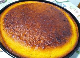 Ένα ταψί αφράτο και σιροπιαστό Ρεβανί Βέροιας, πασπαλισμένο με ινδοκάρυδο, σε ένα πιάτο, με φόντο φλιτζάνι καφέ και λεμόνια.