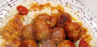 Ένα πιάτο με λευκό ρύζι φούρνου και από πάνω ζεστά κεφτεδάκια περιχυμένα με κόκκινη σάλτσα.