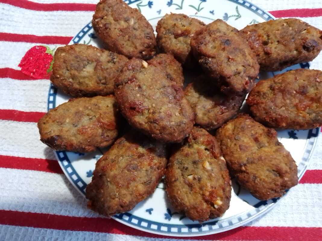 Ένα πιάτο γεμάτο χρυσαφένιους, στρογγυλούς μελιτζανοκεφτέδες με φέτα, έτοιμους για σερβίρισμα.