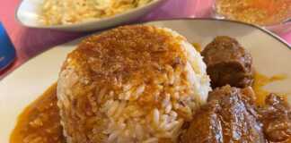 Ένα πιάτο με μαγειρεμένο μοσχάρι σε σκούρα κόκκινη, δεμένη σάλτσα, δίπλα σε ένα βουναλάκι από σπυρωτό λευκό ρύζι.