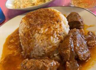 Ένα πιάτο με μαγειρεμένο μοσχάρι σε σκούρα κόκκινη, δεμένη σάλτσα, δίπλα σε ένα βουναλάκι από σπυρωτό λευκό ρύζι.