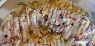 Φιλέτα γαύρου έτοιμα, στρωμένα με ψιλοκομμένο σκόρδο σε στρώσεις.