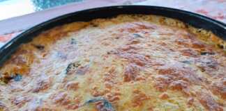 Ένα ταψί με χρυσαφένιες μελιτζάνες σουφλέ, φρεσκοψημένο, με τις στρώσεις των υλικών ορατές και το τυρί λιωμένο και ροδισμένο στην επιφάνεια.