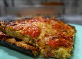 Μια ψημένη ομελέτα σε ένα τετράγωνο πυρέξ, με κολοκυθάκια, κομμάτια ντομάτας και λιωμένο τυρί στην επιφάνεια.