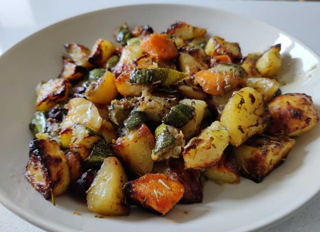 Ένα πιάτο γεμάτο με χρωματιστά ψητά λαχανικά (πατάτες, καρότα, κολοκυθάκια, σκόρδο, λεμόνι) και φρέσκο δεντρολίβανο, μόλις βγαλμένα από το φούρνο.