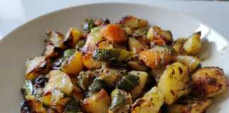 Ένα πιάτο γεμάτο με χρωματιστά ψητά λαχανικά (πατάτες, καρότα, κολοκυθάκια, σκόρδο, λεμόνι) και φρέσκο δεντρολίβανο, μόλις βγαλμένα από το φούρνο.