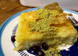 Ένα ταψί με λαχταριστή, χρυσαφένια σιροπιαστή μπουγάτσα με κρέμα τυριού, πασπαλισμένη με λίγα φιστίκια Αιγίνης, έτοιμη για σερβίρισμα.