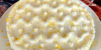 Μία ολόκληρη Τούρτα Λεμονιού, διακοσμημένη με φέτες λεμονιού και ξύσμα, σε μία πιατέλα