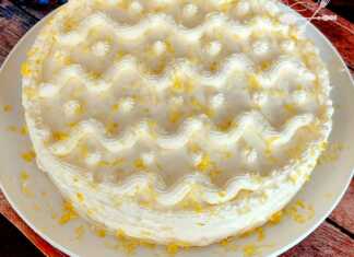 Μία ολόκληρη Τούρτα Λεμονιού, διακοσμημένη με φέτες λεμονιού και ξύσμα, σε μία πιατέλα