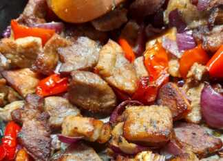 Ζουμερή χοιρινή τηγανιά στο τηγάνι με πολύχρωμες πιπεριές, κρεμμύδι και φρέσκο λεμόνι