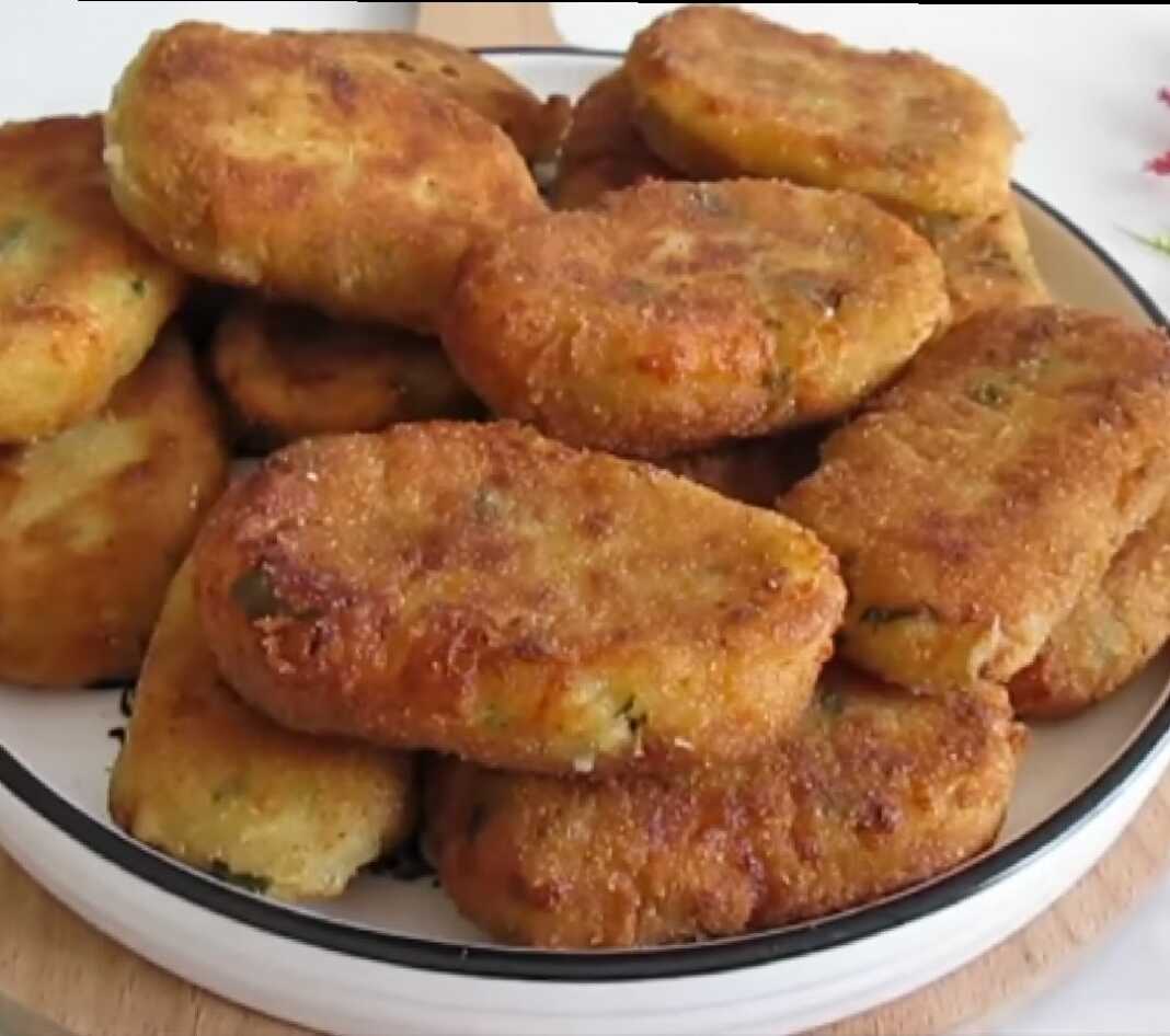 Ένα πιάτο με χρυσαφένιες, τηγανητές πατατοκροκέτες που έχουν τυρί στο εσωτερικό τους.