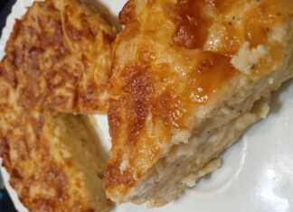 Ένα κομμάτι χρυσαφένιας κασερόπιτας χωρίς φύλλο σε ένα λευκό πιάτο. Η πίτα φαίνεται αφράτη και έχει τριμμένο κασέρι στην επιφάνεια.