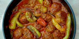 Μια κατσαρόλα γεμάτη με κεφτεδάκια και πιπεριές κέρατο μέσα σε πλούσια κόκκινη σάλτσα ντομάτας.