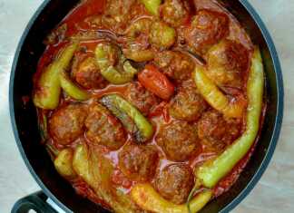 Μια κατσαρόλα γεμάτη με κεφτεδάκια και πιπεριές κέρατο μέσα σε πλούσια κόκκινη σάλτσα ντομάτας.