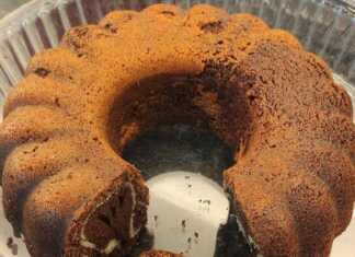 Κομμάτι από δίχρωμο κέικ βανίλια σοκολάτα δίπλα σε μια κούπα ζεστό καφέ πάνω σε ξύλινη επιφάνεια