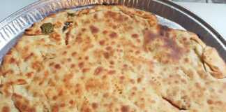 Μια χρυσαφένια, τηγανισμένη Σαΐτια, κομμένη σε κομμάτια, με πρασινάδα (πιθανόν δυόσμο) να φαίνεται από τη γέμιση.