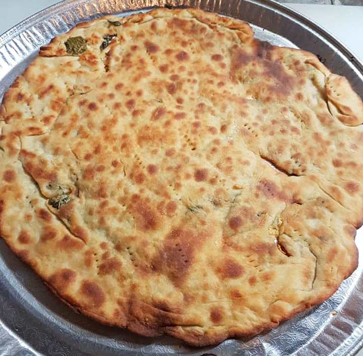 pitaTigani Μια χρυσαφένια, τηγανισμένη Σαΐτια, κομμένη σε κομμάτια, με πρασινάδα (πιθανόν δυόσμο) να φαίνεται από τη γέμιση.