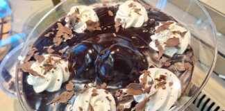 Ένα μπολ γεμάτο σπιτικό προφιτερόλ με στρώσεις από σουδάκια, πλούσια σοκολάτα και σαντιγί, διακοσμημένο με τριμμένη σοκολάτα.