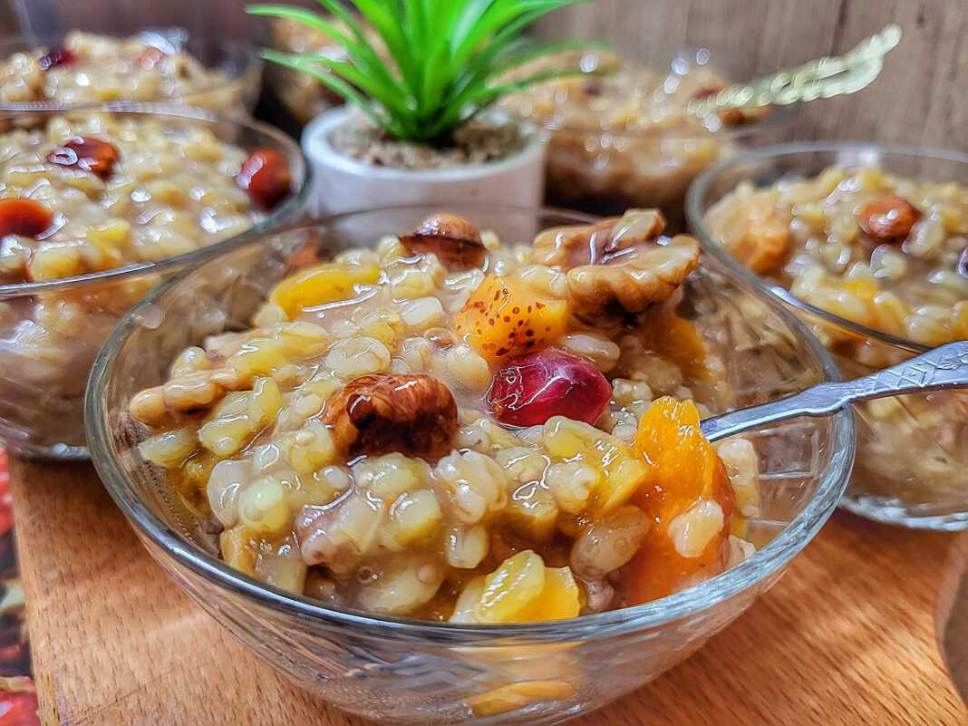 varbara Γλυκός χυλός Βαρβάρα (Ασουρέ) σε μικρό μπολ, διακοσμημένος στην επιφάνεια με καρύδια, ρόδι και κανέλα.