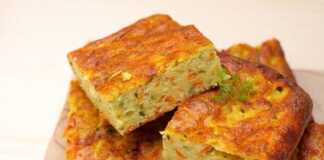 Μια φέτα πολύχρωμης κολοκυθόπιτας που φαίνονται το πράσινο από τα κολοκυθάκια και το πορτοκαλί από το καρότο.