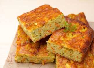 Μια φέτα πολύχρωμης κολοκυθόπιτας που φαίνονται το πράσινο από τα κολοκυθάκια και το πορτοκαλί από το καρότο.