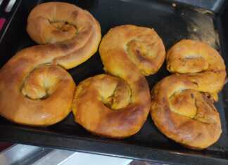 Τρεις κιμαδόπιτες σε σχήμα S τοποθετημένες σε ένα ταψί, με χρυσαφένιο χρώμα και λιωμένο βούτυρο στην επιφάνεια.