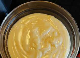 Λεία, κίτρινη κρέμα ζαχαροπλαστικής σε γυάλινο μπολ, καλυμμένη με μεμβράνη που εφάπτεται στην επιφάνεια.