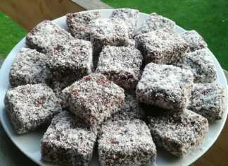 Ένα πιάτο γεμάτο με τετράγωνα γλυκάκια κέικ, καλυμμένα με σκούρα σοκολάτα και πασπαλισμένα με τριμμένη καρύδα.