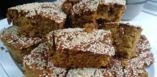 Μια φρεσκοψημένη, χρυσαφένια σταφιδόπιτα, πασπαλισμένη με σουσάμι, κομμένη σε κομμάτια, που αναδεικνύει τις ζουμερές σταφίδες στο εσωτερικό.