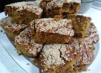 Μια φρεσκοψημένη, χρυσαφένια σταφιδόπιτα, πασπαλισμένη με σουσάμι, κομμένη σε κομμάτια, που αναδεικνύει τις ζουμερές σταφίδες στο εσωτερικό.