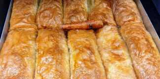 Ένα ταψί με χρυσαφένια, τραγανά ατομικά γαλακτομπούρεκα, περιχυμένα με σιρόπι.