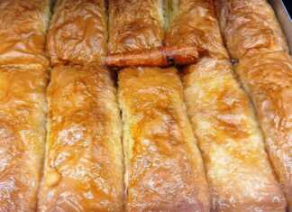 Ένα ταψί με χρυσαφένια, τραγανά ατομικά γαλακτομπούρεκα, περιχυμένα με σιρόπι.