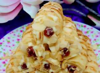 Σειρά από σιροπιαστά κορνεδάκια γεμισμένα με πλούσια κρέμα και γαρνιρισμένα με τριμμένο αμύγδαλο και κόκκινα κερασάκια