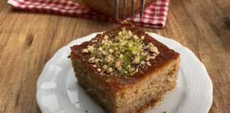 Ένα κομμάτι ρεβανί με καρύδια, αναδεικνύοντας την υγρή του ψίχα και την πλούσια γέμιση.