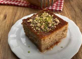 Ένα κομμάτι ρεβανί με καρύδια, αναδεικνύοντας την υγρή του ψίχα και την πλούσια γέμιση.