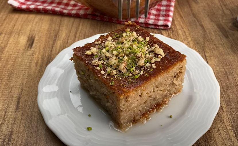 revaniPortokali Ένα κομμάτι ρεβανί με καρύδια, αναδεικνύοντας την υγρή του ψίχα και την πλούσια γέμιση.