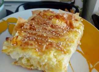 Χρυσαφένια, φουσκωτή πατσαβουρόπιτα σε ταψί, με εμφανείς τις πτυχώσεις του φύλλου και το σουσαμι να την καλύπτει.