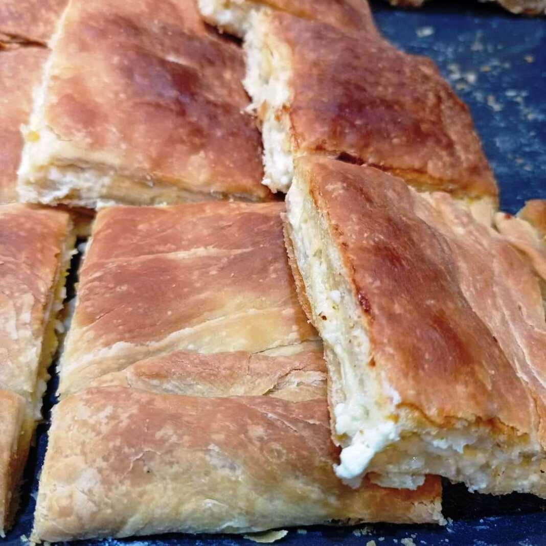 Κοντινό πλάνο σε κομμάτια πό Τυρόπιτα με σπιτικό φύλλο, που αναδεικνύει τις στρώσεις του φύλλου και την πλούσια τυρένια γέμιση.