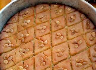 Χρυσαφένιο ραβανί στο ταψί χαραγμένο σε ρόμβους με τρία ξασπρισμένα αμύγδαλα σε κάθε κομμάτι