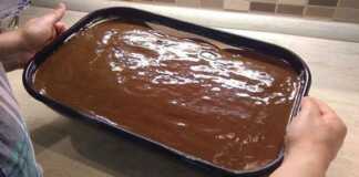 Μια πλούσια τούρτα σοκολάτας με στρώσεις παντεσπάνι και κρέμα μασκαρπόνε, καλυμμένη με γυαλιστερό γλάσο σοκολάτας, κομμένη σε τετράγωνα κομμάτια.