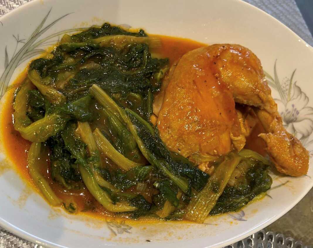 Πιάτο με κοτόπουλο με χόρτα, σε κόκκινη σάλτσα, γαρνιρισμένο με άνηθο.